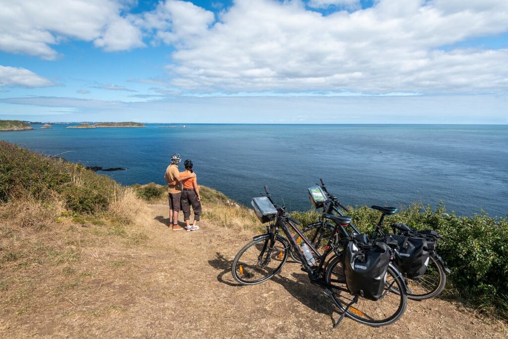 Couple à vélo qui admire le paysage littoral de la baie de Paimpol en Bretagne